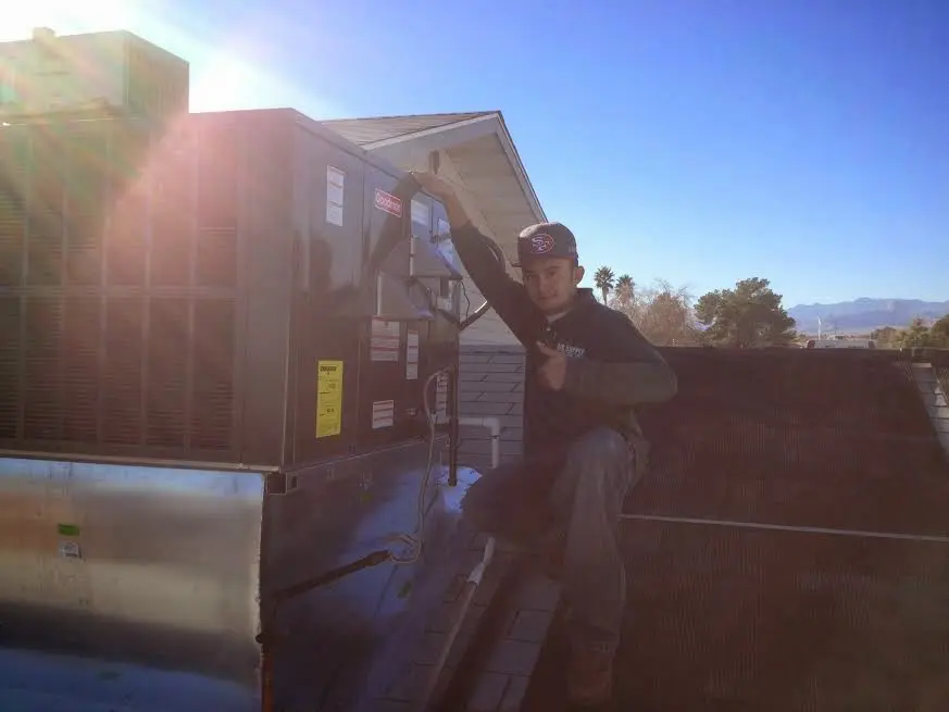 HVAC technician performing Heat Pump Repair on a rooftop unit in Scriba